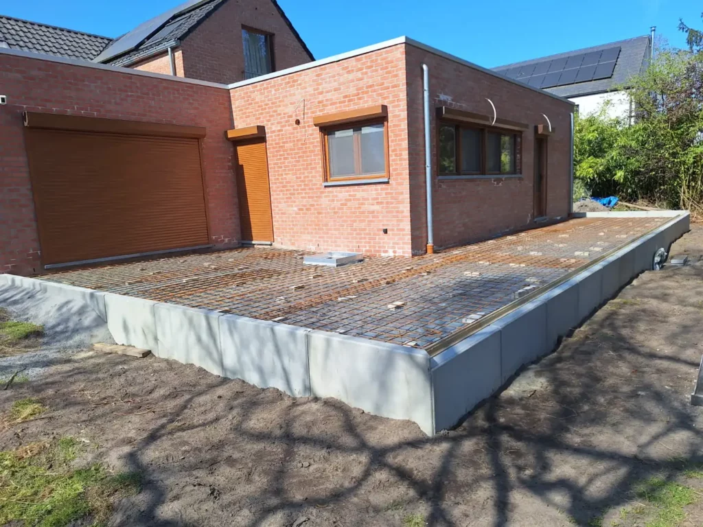 Terrasse en construction avec treillis métallique le long d'une maison en briques