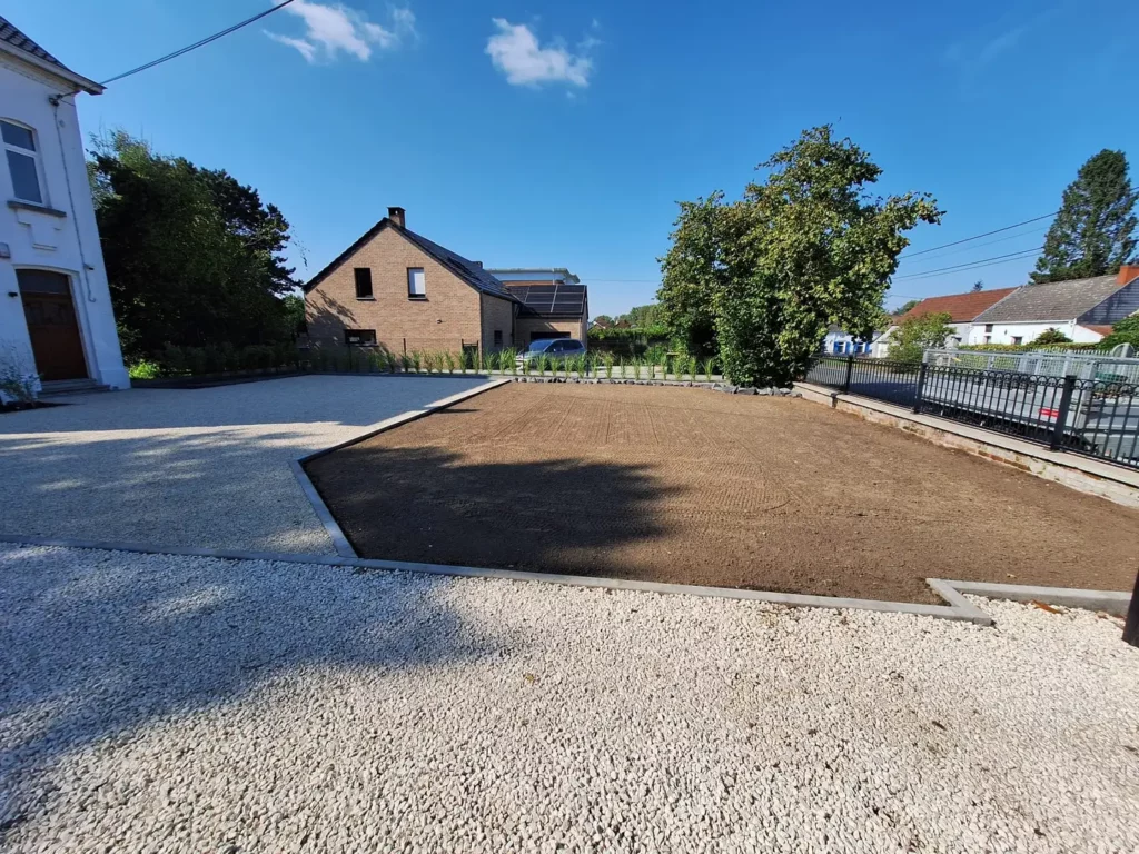 Allée de gravier et parterre de terre préparé le long d'une maison blanche