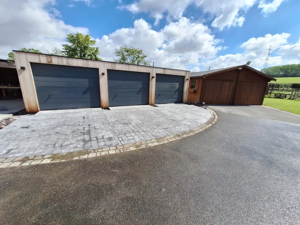 Pavés et enrobé courbe devant un bloc de trois garages